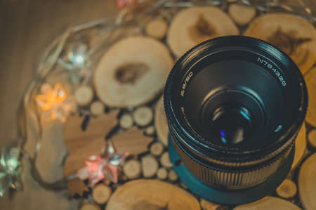 Soviet old lens with manual focus on a decorative wooden stand. Warm light. Top view, close upの写真素材