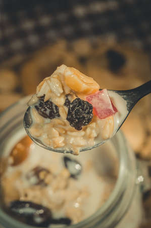 Glass jar with a healthy breakfast of oatmeal with nuts, dried fruits and yogurt. Early morning, top view, close upの写真素材