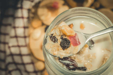 Glass jar with a healthy breakfast of oatmeal with nuts, dried fruits and yogurt. Early morning, top view, close upの写真素材