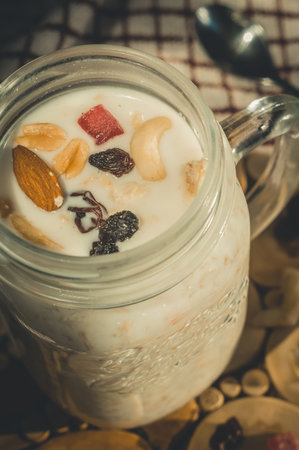 Glass jar with a healthy breakfast of oatmeal with nuts, dried fruits and yogurt. Early morning, top view, close upの写真素材