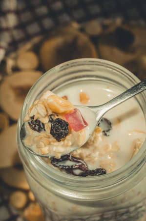 Glass jar with a healthy breakfast of oatmeal with nuts, dried fruits and yogurt. Early morning, top view, close upの写真素材