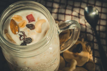 Glass jar with a healthy breakfast of oatmeal with nuts, dried fruits and yogurt. Early morning, top view, close upの写真素材