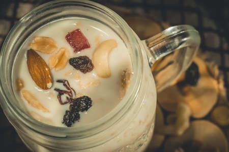 Glass jar with a healthy breakfast of oatmeal with nuts, dried fruits and yogurt. Early morning, top view, close upの写真素材
