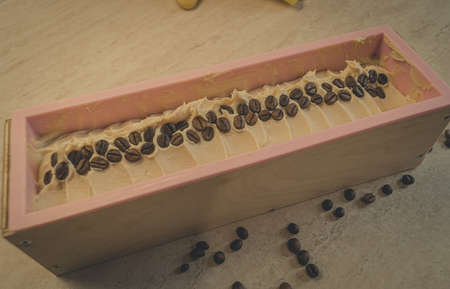 Preparation of handmade soap. The base for soap in silicone form, decorated with coffee beans. Horizontal composition, copy space, color toningの写真素材