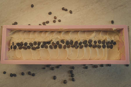 Preparation of handmade soap. The base for soap in silicone form, decorated with coffee beans. Top view, horizontal composition, copy space, color toningの写真素材