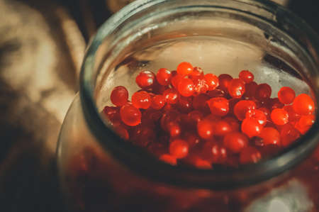 Harvest of berries in glass jars. Stone berry, kostyanika, rubus saxatilis. Rustic style, dark photo, copy space, horizontal compositionの写真素材