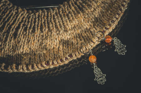 Decorative markers for knitting. Metal and stone. Hand knitting. Dark background, close-up, copy space, horizontal compositionの写真素材