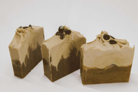 Three pieces of handmade soap with coffee aroma and coffee beans. Hobby - soap making. White background, copy space, isolated objectsの写真素材