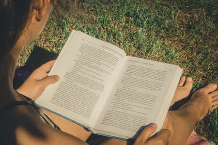 The girl reads a book about spiritual practices. An open book in hand. The text of the pages in Russian language.の写真素材