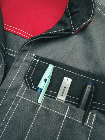 Close-up of work clothes with writing pens and markers in pockets.