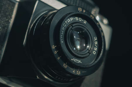 Close-up of the Soviet manual lens Industar 50-2 on a film camera Zenit-E. Black background, selective focus, blur, copy space, deep shadows, horizontal compositionのeditorial素材