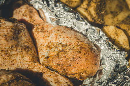 Pickled chicken legs in foil for baking. Cooking in the oven. Close-up, selective focusの写真素材