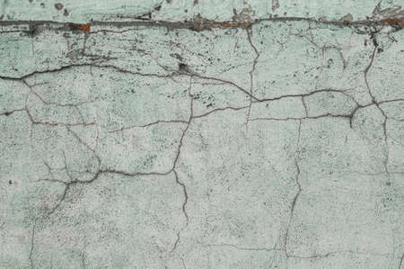 The texture of an old concrete wall with cracks and faded paint. Destruction of the outer wall under the influence of time and weather conditions.の写真素材
