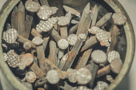 Old iron nails close-up in an iron jar. Iron pin covered with dust and rust. Selective focus, grain, blur, defocused, dust on surface.の写真素材
