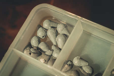 Box with a set of fishing sinkers. Lead sinkers of different weights. Equipment and accessories for fishing. Selective focus.の写真素材