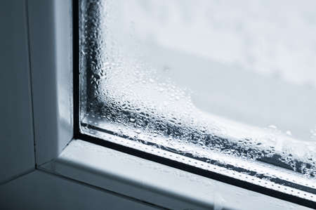Condensation on the glass. Defective plastic window. Sweating windows in the house. Drops of water on the glass. Selective focus.の写真素材
