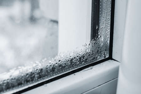 Defective plastic window with condensation formed on the glass. Detection of a lack of double-glazed windows. Selective focusの写真素材