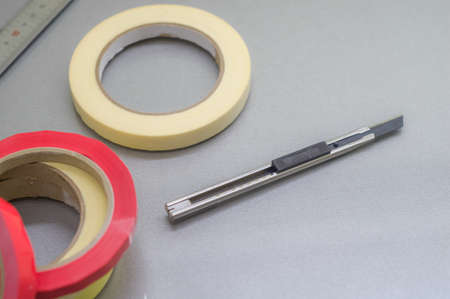 Several rollers of adhesive tape for different purposes. Paint and duct tape. Stationery knife. Selective focus.の写真素材
