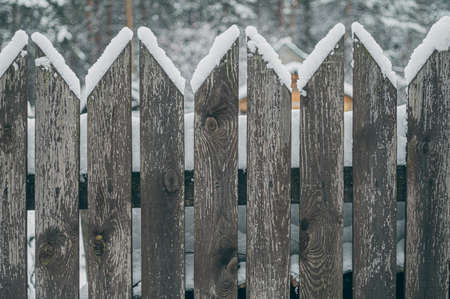 An old wooden picket fence in the village in winter. Snow on the fence. Selective focusの写真素材