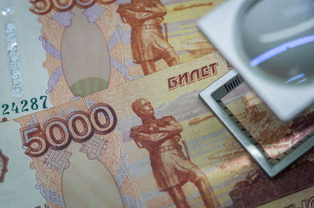 Verification of Russian banknotes for authenticity under a magnifying glass. Used money. Selective focusの写真素材