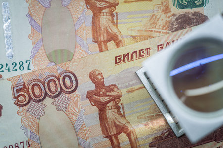 Verification of Russian banknotes for authenticity under a magnifying glass. Used money. Selective focusの写真素材