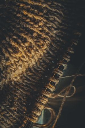 Knitting project close-up. Loops of yarn on the spokes. Knitting a warm sweater. Dark background, vertical compositionの写真素材