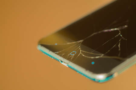 Blurred smartphone with broken display glass. Cracked screen glass. Broken phone. Selective focusの写真素材