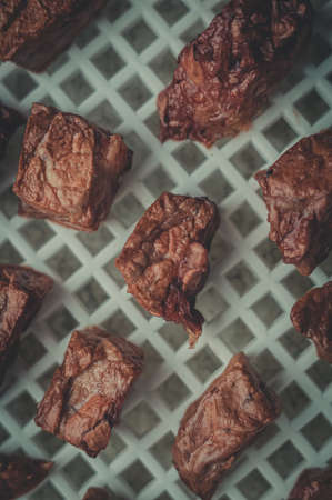 Blurred dried pieces of meat in the tray of an electric dryer. Preparation of dehydrated meat for storage. Selective focus, blur. Top view, vertical composition, close-upの写真素材