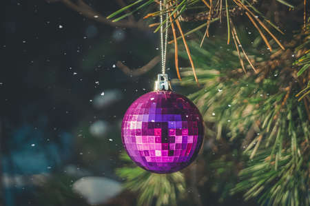A shiny glass ball hangs on a branch of a Christmas tree. Christmas decoration. Preparing for New Year. Selective focus, copy space, outsideの写真素材