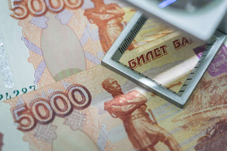 Verification of Russian blurred banknotes for authenticity under a magnifying glass. Used money. Selective focusの写真素材