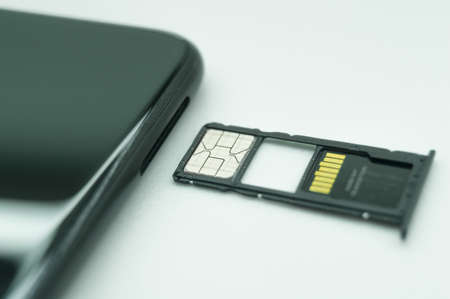 Open tray of SIM cards of the mobile operator and micro memory card of the smartphone. Installation of a new SIM card. Selective focus, white backgroundの写真素材