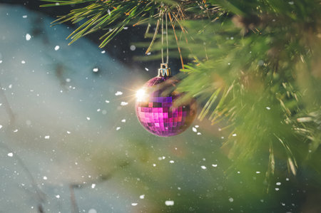 Blurred shiny glass ball hangs on a branch of a Christmas tree. Christmas decoration. Preparing for New Year. Selective focus, copy space, outsideの写真素材