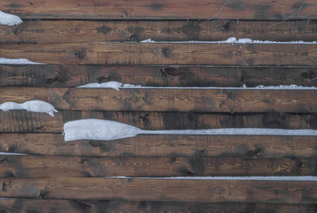Wooden solid fence made of boards with snow. Abstract background, selective focusの写真素材