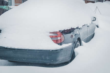 A car under a snow drift. Heavily snow-covered car in the parking lot. Selective focusの写真素材
