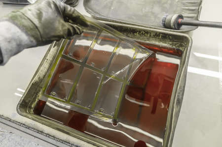The process of manual washing of polymer printing plates in a special solution dissolving the paint. Work in a printing house. Selective focusの写真素材