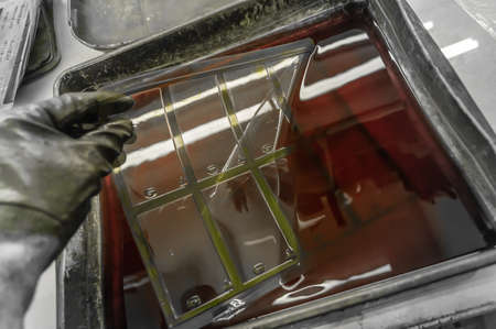 The process of manual washing of polymer printing plates in a special solution dissolving the paint. Work in a printing house. Selective focusの写真素材
