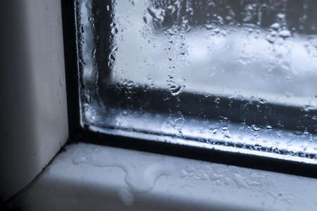 Condensate drops on the glass of a plastic window. Freezing and the formation of condensation and mold on the new plastic window. Defect in installation. Problem. Selective focusの写真素材