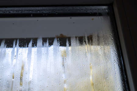 Condensate drops on the glass of a plastic window. Freezing and the formation of condensation and mold on the new plastic window. Defect in installation. Problem. Selective focusの写真素材