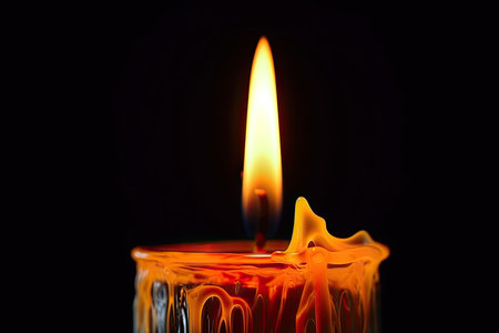 This is a close-up photo of a candle flame with a bright yellow color, set against a dark background. The flame appears to be burning steadily and emitting a warm glow, which creates a peaceful and calming atmosphere.の素材