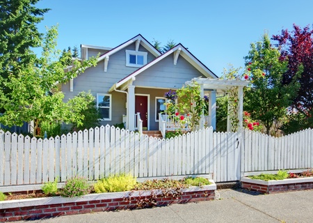 Grey small cute house with white fence and roses.の写真素材