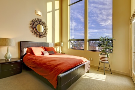 Large high ceiling bedroom with red bed and yellow walls.の写真素材