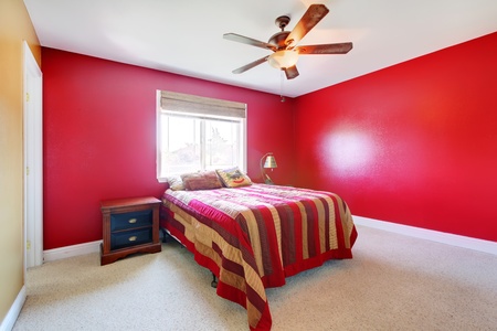 Simple red bedroom with bed and nightstand.の写真素材