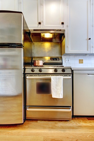 Stove and refrigerator in stainless steal with white kitchen and hardwood floor.の写真素材