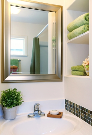 New beautiful white sink with green towels and mirror with white shelves.の写真素材