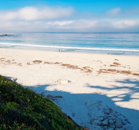 White sand with blue water near carmel, California with couple walking.の写真素材
