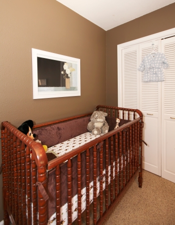 Cherry wood baby crib in nursery interior with brown wall.の写真素材