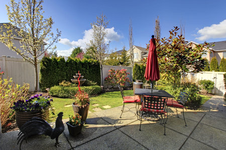 Spring house back yard with red chairs and umbrella and nice landscape.