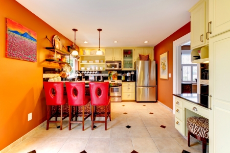 Small kitchen room with yellow wooden cabinets and red bar stoolsの写真素材