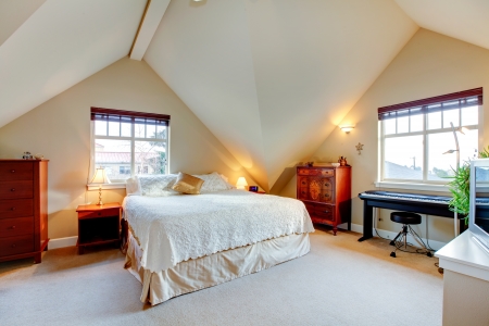Vaulted ceiling  bright bedroom with wood furniture and pianoの写真素材