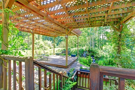 Farm house backyard deck view. Pond and waterfall, covered patio area with rustic old bench and flower potsの写真素材